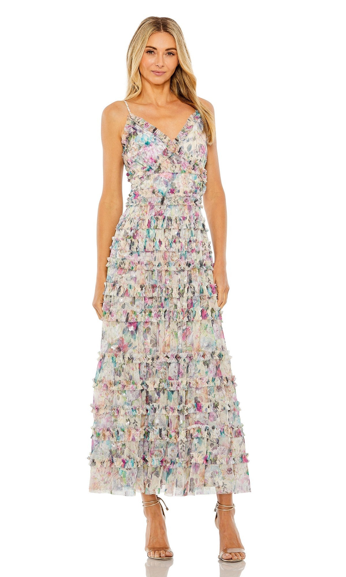 A woman stands in a Mac Duggal 8095 Tea-Length Party Dress in Nude Multi, showcasing multicolored floral prints and elegant ruffle detailing, paired with strappy heels against a white background.